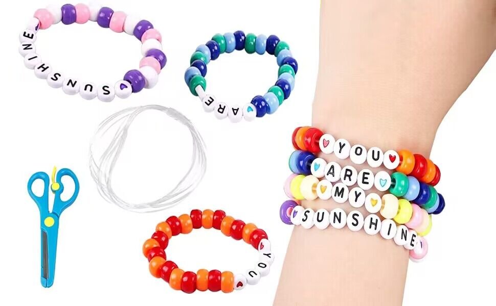 Beaded bracelets with text, scissors, and string for jewelry making.