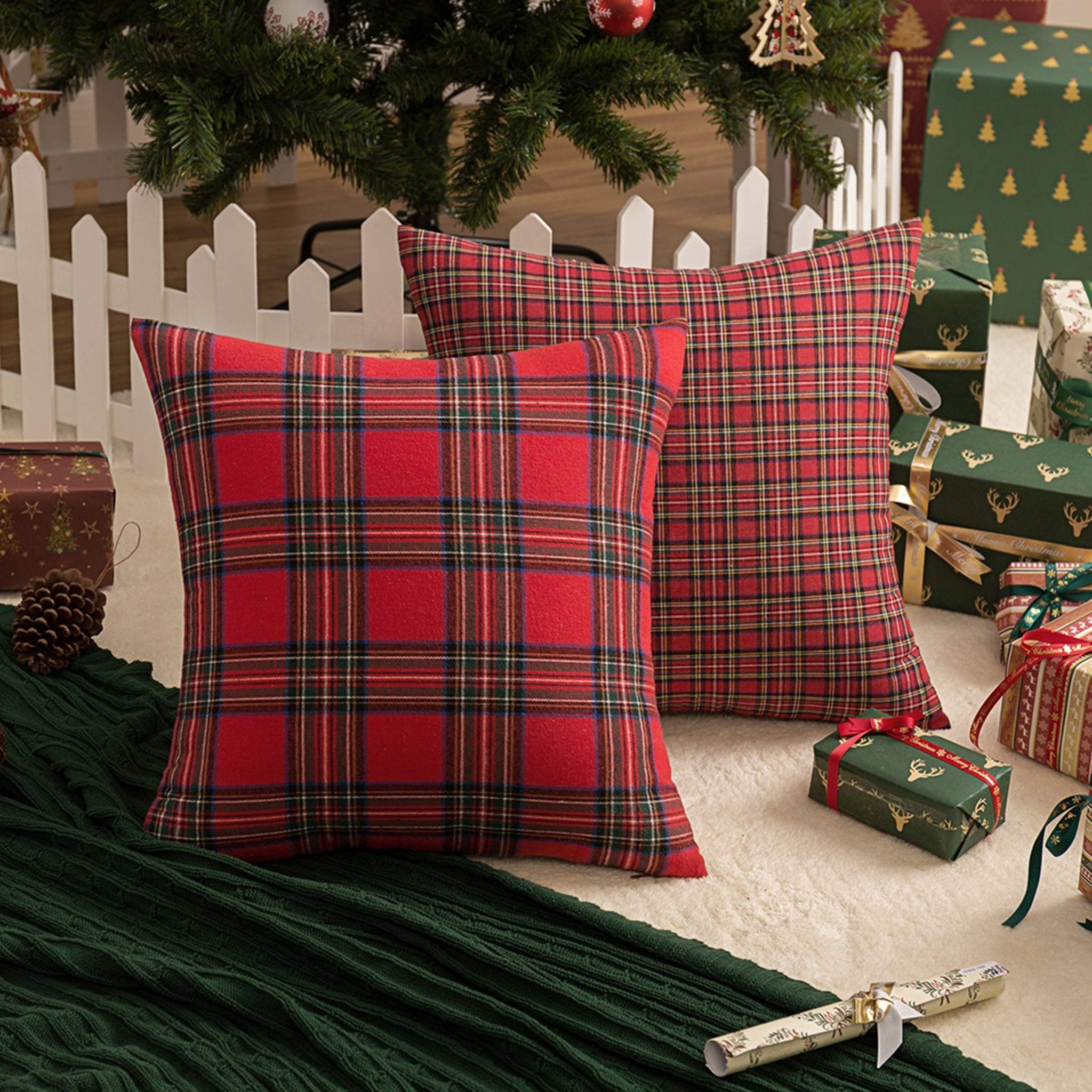 Two red and green plaid Christmas throw pillow covers arranged with gifts and a Christmas tree.