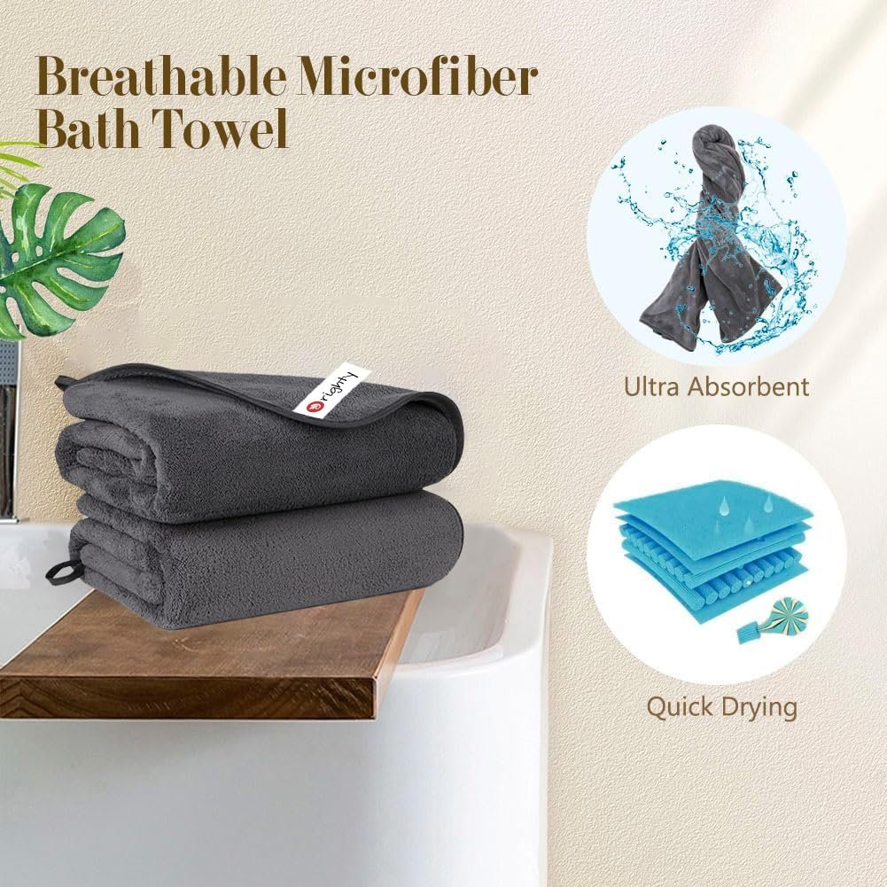 Stack of two grey microfiber bath towels on a wooden shelf over a bathtub, with graphics showing absorbency and quick drying features.