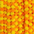 Close-up of orange and yellow artificial marigold flower garlands, densely packed.