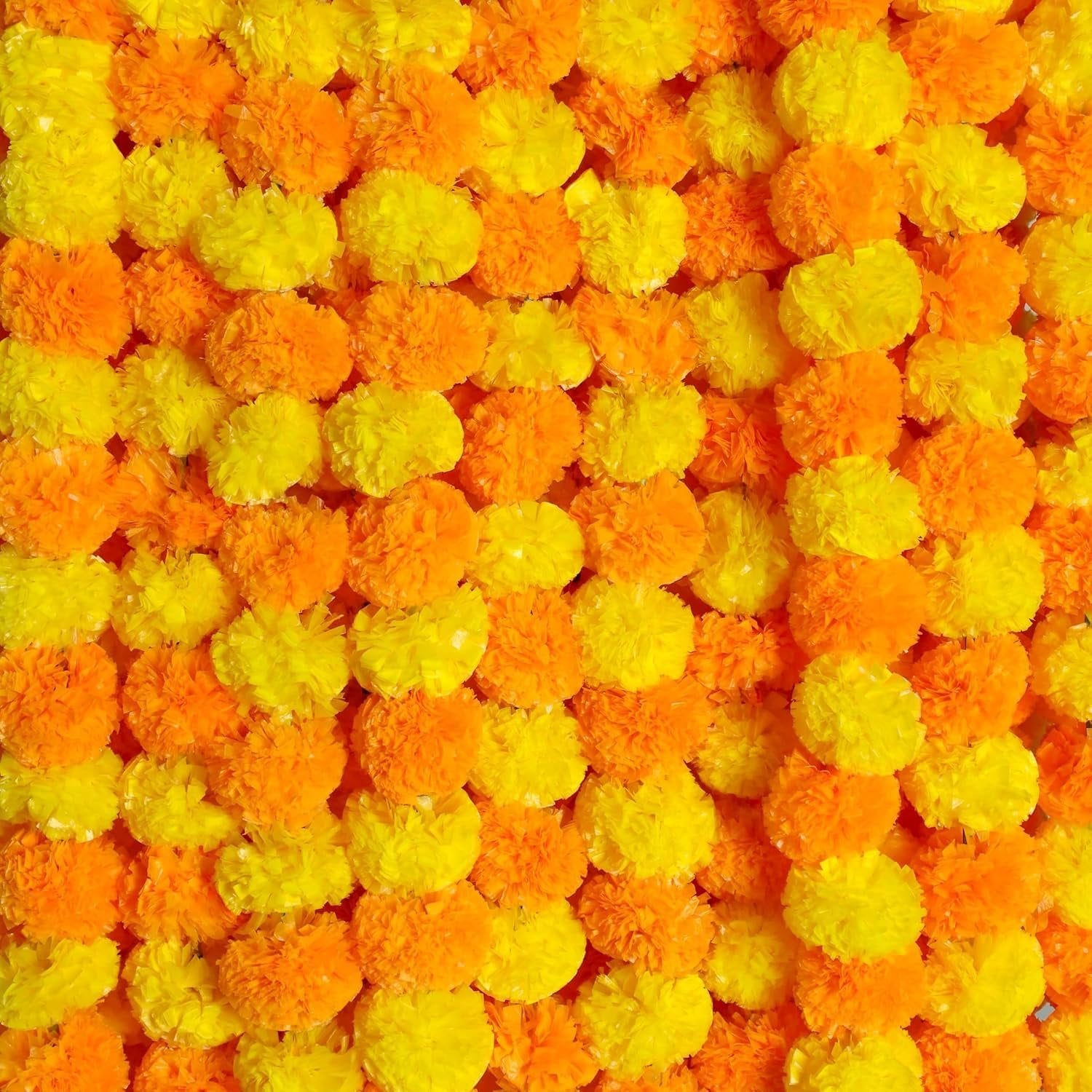 Close-up of orange and yellow artificial marigold flower garlands, densely packed.