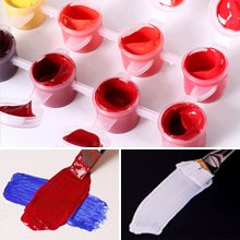 Paint by number kit with multiple small pots of acrylic paint and brushes showing swatches of red, blue, and white paint.