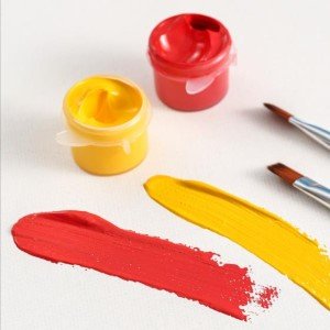 Paint by numbers kit with red and yellow acrylic paint pots and swatches, plus two brushes on a white surface.