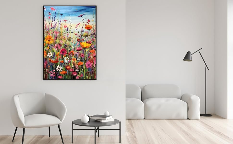 Framed vibrant floral painting hanging on a wall above a chair and table in a modern living room setting.