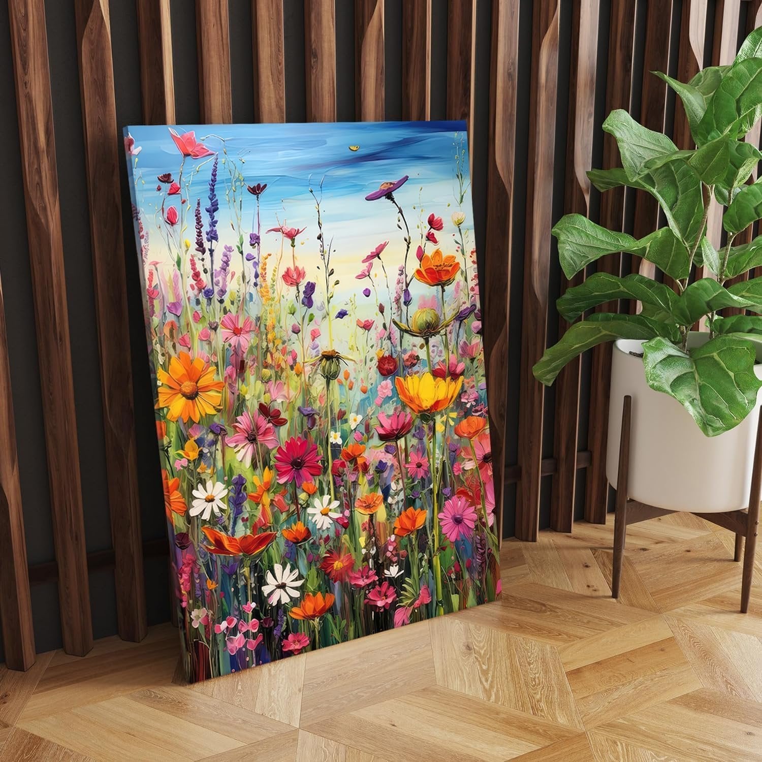 Vibrant floral painting on canvas leaning against a wooden wall with a potted plant nearby.