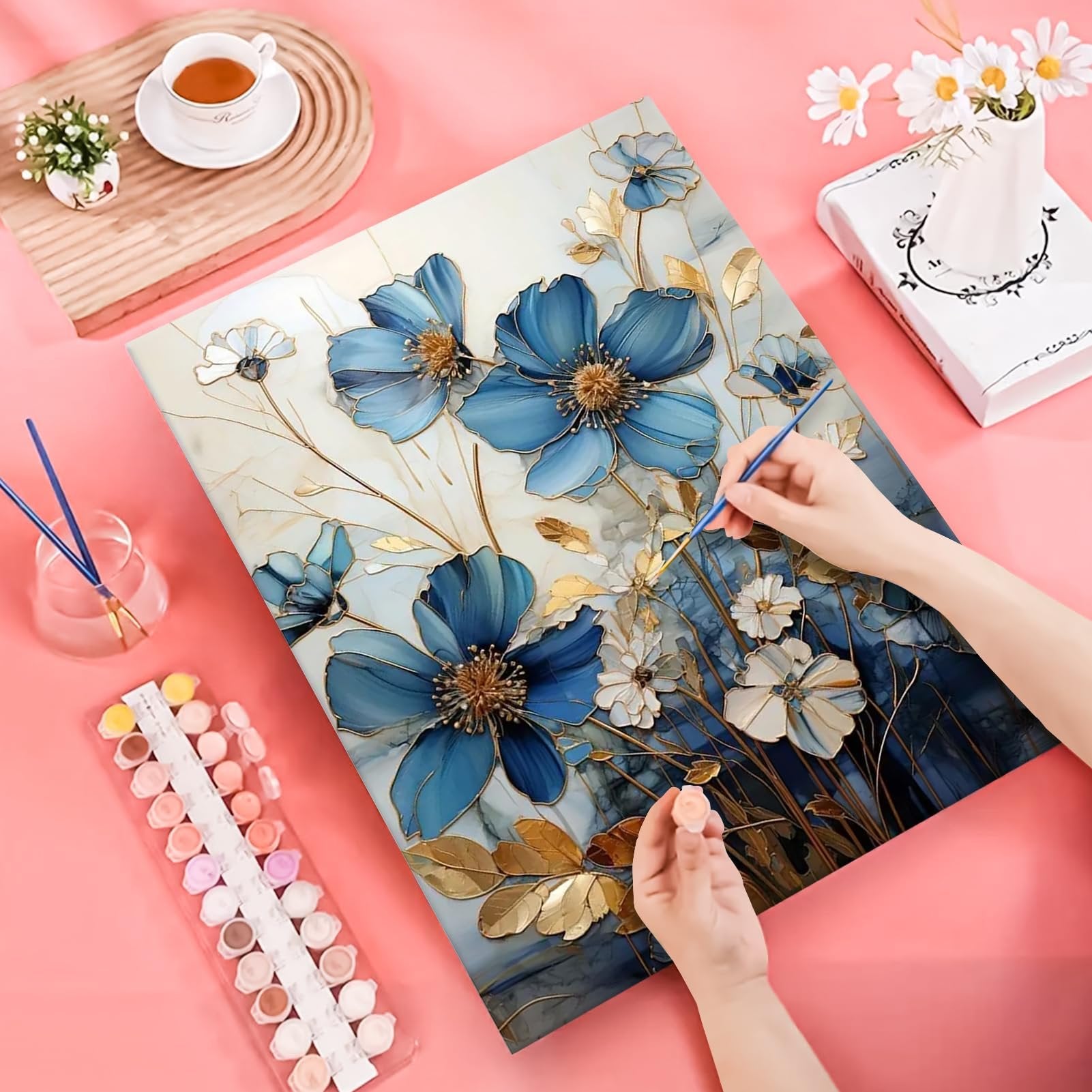 Hands painting a floral design on a numbered canvas with acrylic pigments and brushes.