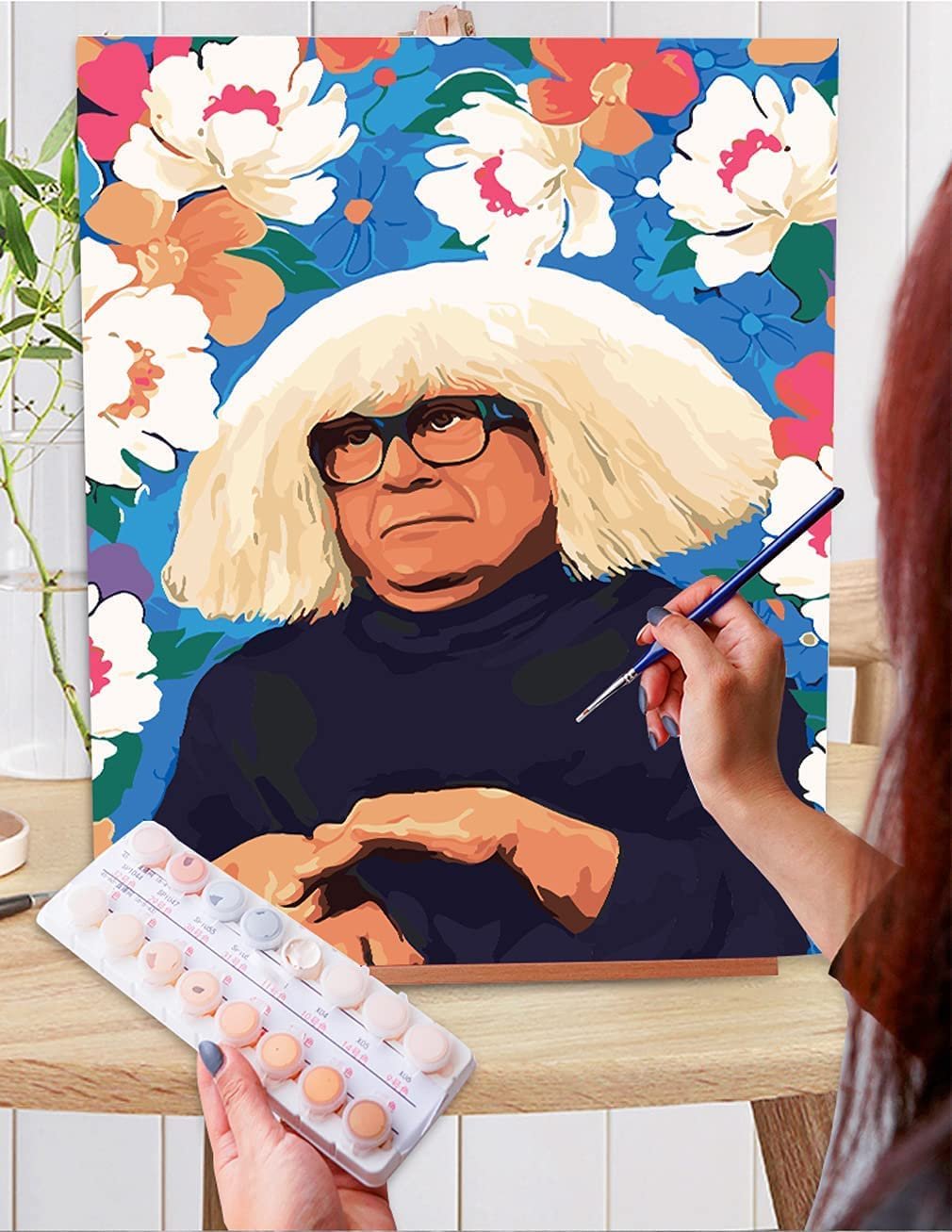 Paint by numbers kit showing a portrait of a man with a white wig and glasses, with floral background, and paint pots.