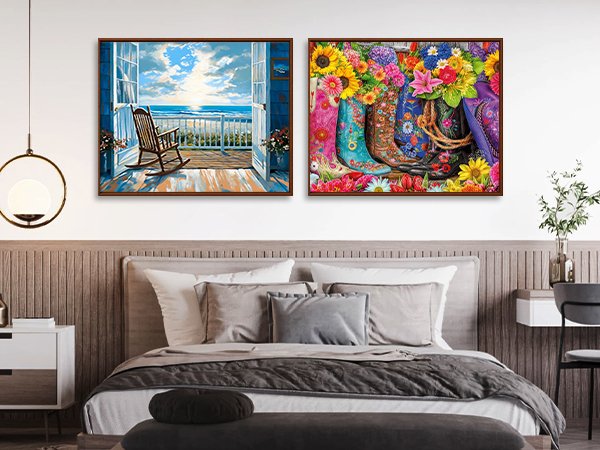 Two framed paint by numbers canvases displayed above a bed, one with a rocking chair on a balcony overlooking the ocean, the other with cowboy boots filled with flowers.