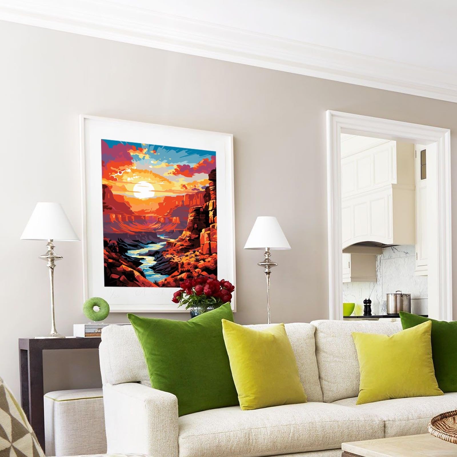 Framed painting of a canyon river at sunset hanging above a sofa with green pillows