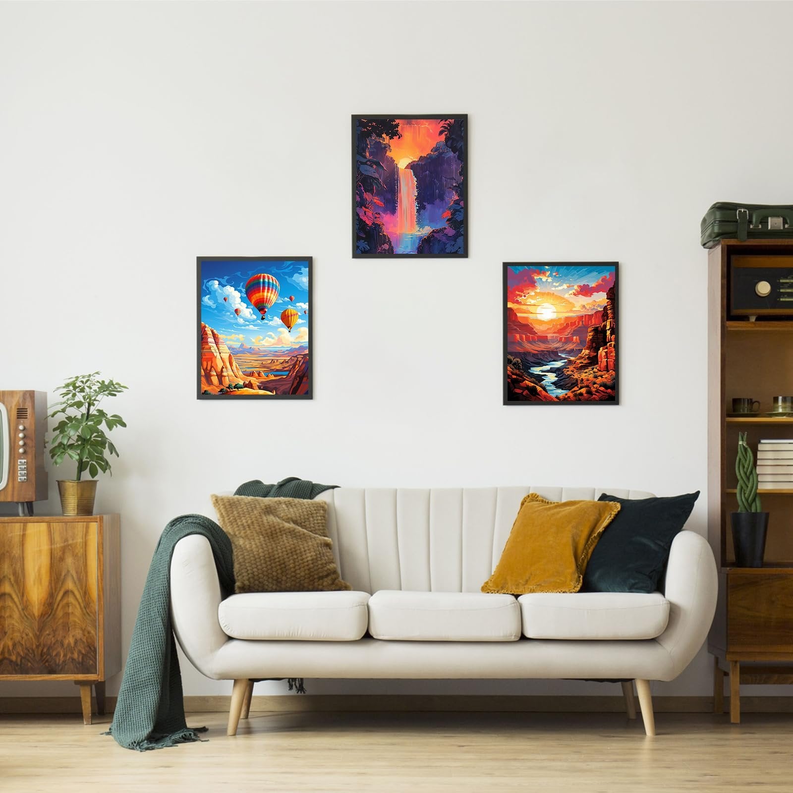 Three framed landscape art prints hanging on a wall above a sofa, featuring hot air balloons, a waterfall, and a canyon sunset.