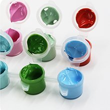 Close-up of paint pots with various colors of acrylic paint, including pink, green, red, and blue, on a white background.