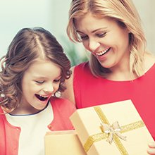 Mother and daughter excitedly opening a gift box with a gold ribbon