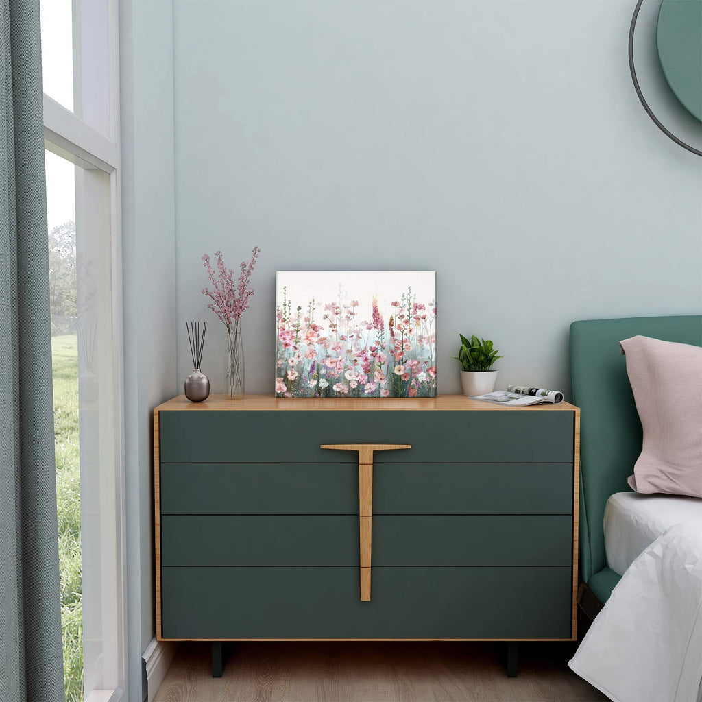 Pink wildflower floral painting displayed on a dark green dresser next to a bed