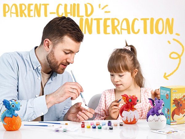 Father and daughter painting dragon craft kits together, with paints and brushes on table.