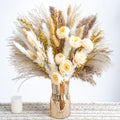 Boho pampas grass and dried flower bouquet in a gold vase with a white candle on a lace runner