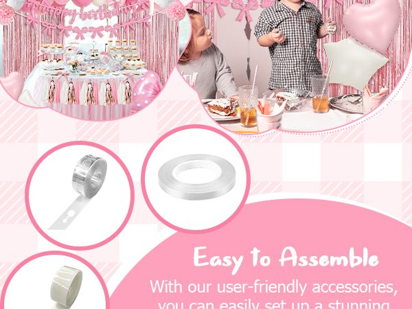 Pink birthday party decorations including banner, balloons, pompoms, tassels, and fringe curtain, with children and a dessert table.