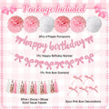 Pink and white birthday party decorations including paper pompoms, happy birthday banner, bow garland, tissue tassels, and bow decorations.