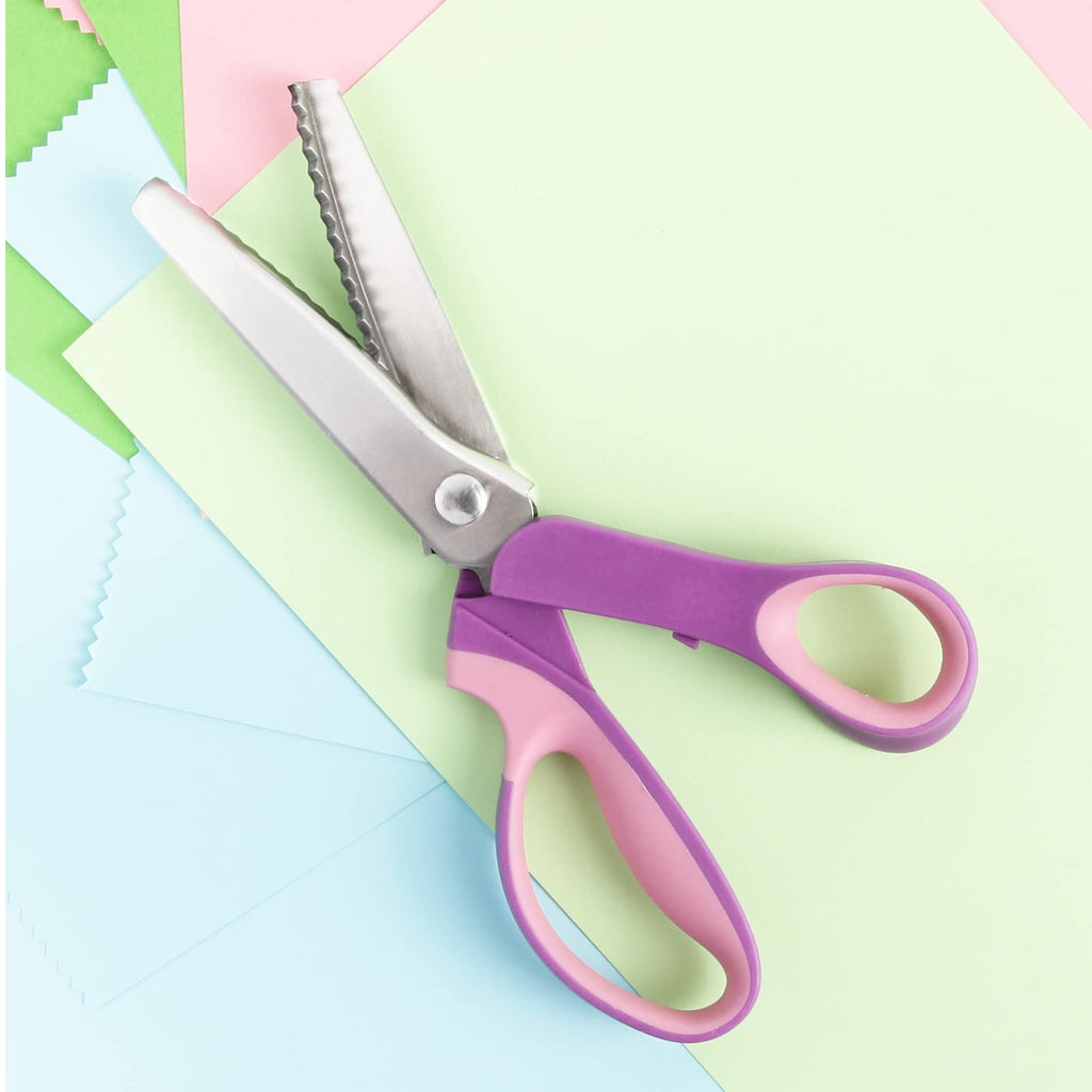 Purple and pink handled pinking shears with zigzag blades, laid on pastel colored paper.