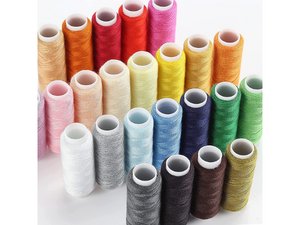 Assortment of colorful sewing thread spools arranged in rows on a white surface.