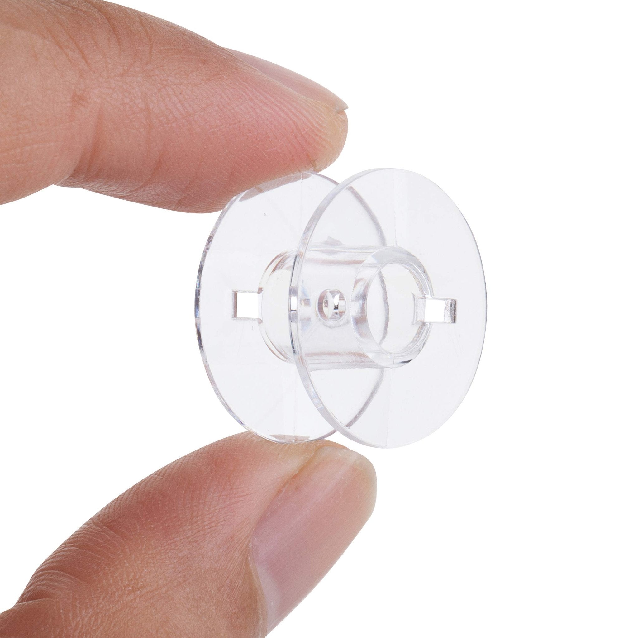 Close-up of a clear plastic sewing machine bobbin held between two fingers against a white background.