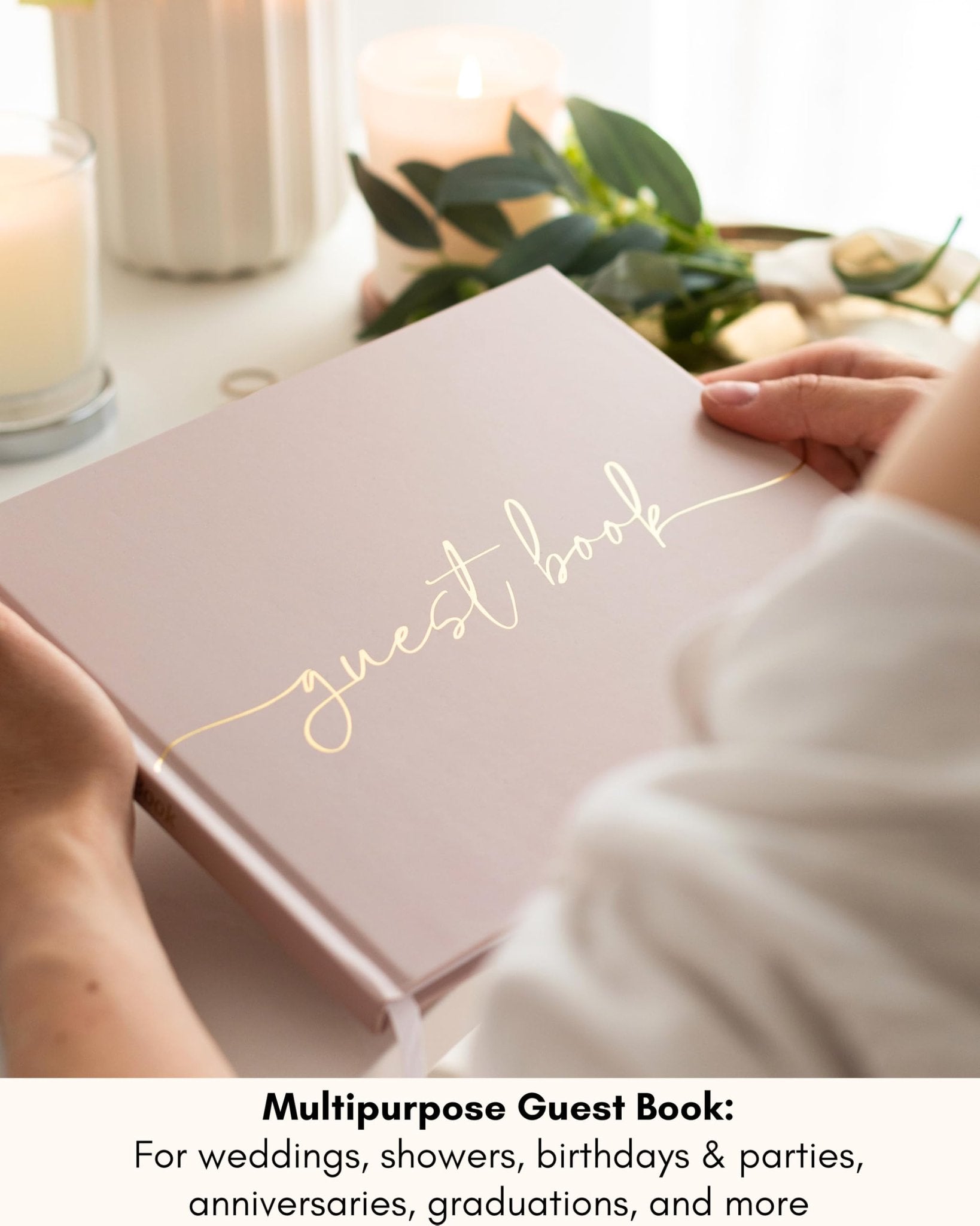 Person holding a pink guest book with gold 'guest book' script on the cover, surrounded by candles and greenery.