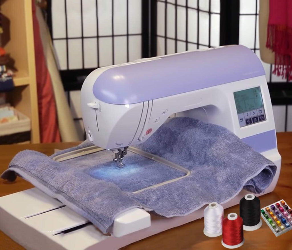 Embroidery machine with a blue towel hooped and ready for stitching, with spools of thread in foreground.