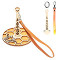 Wooden yarn holder with bee and honeycomb design, includes leather strap and extra components.