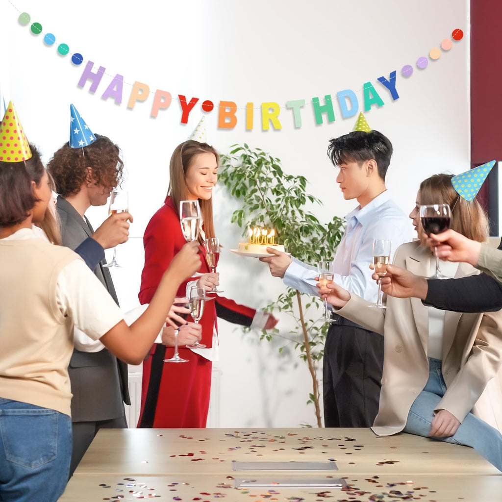 People celebrating a birthday with a cake and a colorful banner that says Happy Birthday.
