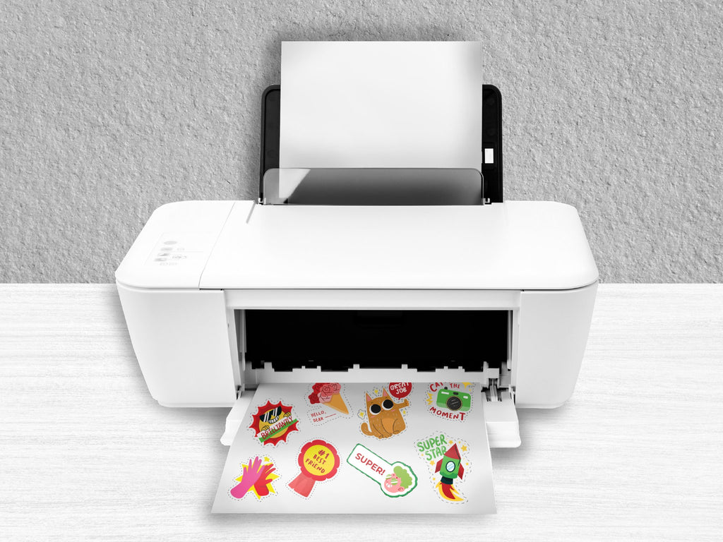 Printer outputting a sheet of paper with various colorful stickers, including a cat, rocket, and camera.