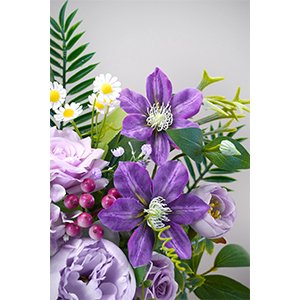 Close-up of a bouquet of artificial purple and pink flowers, including clematis, roses, and berries, with green foliage.