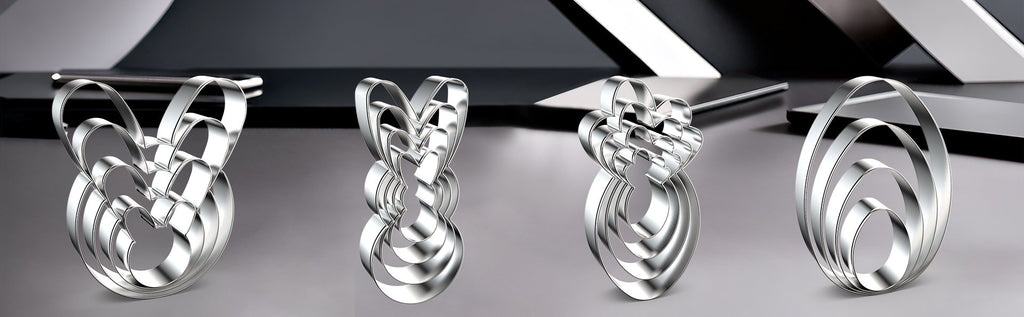 Set of four stainless steel heart-shaped cookie cutters with scalloped edges, displayed on a reflective surface.