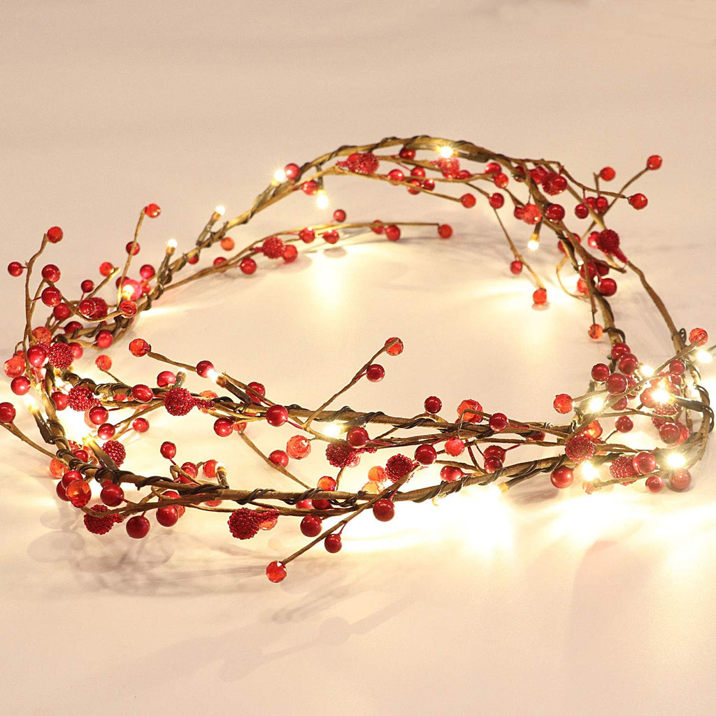 Red berry and LED light garland arranged in a curve on a white surface.
