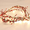 Red berry and LED light garland arranged in a curve on a white surface.