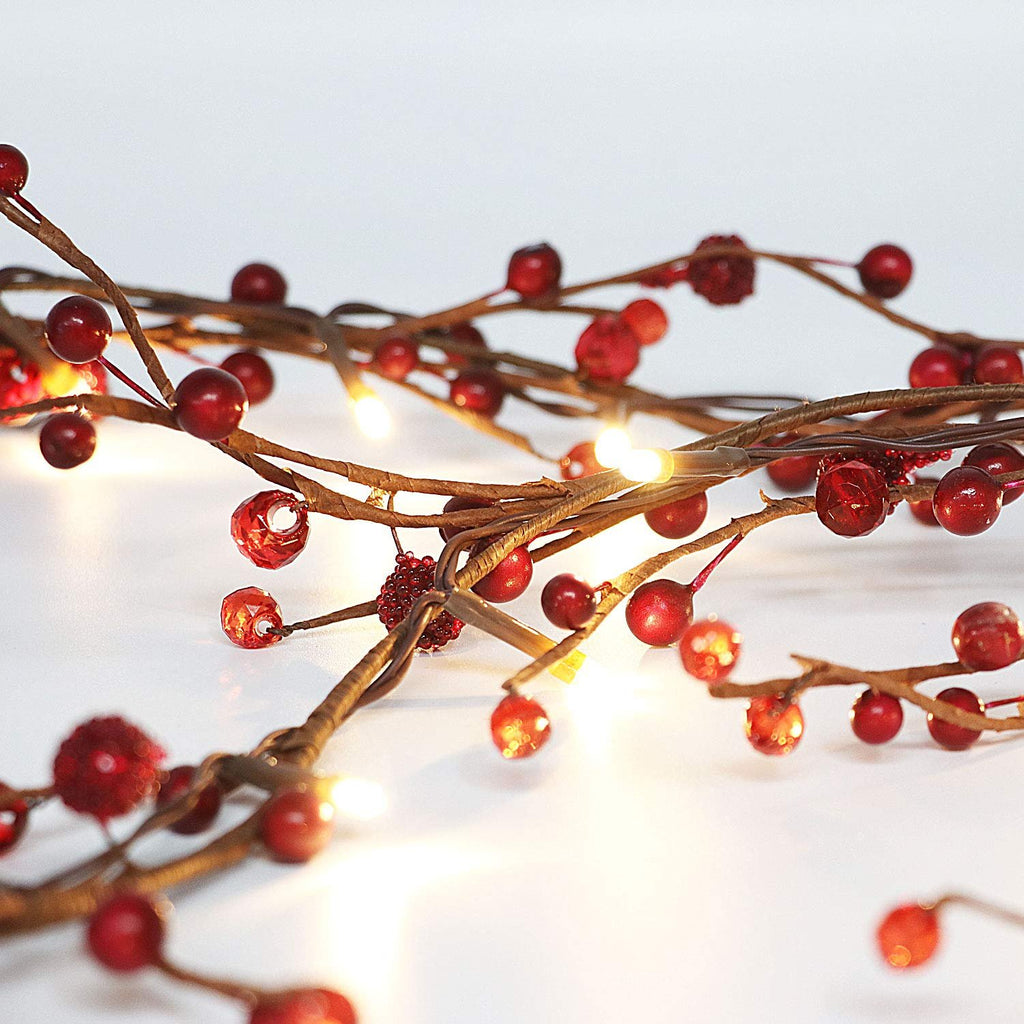 Close-up of a red berry and LED light garland on a white background, showing intricate details of the branches and berries.