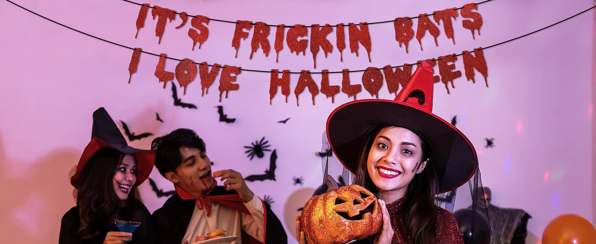 Halloween party with people in costumes and a glitter banner that says 'It's Frickin Bats I Love Halloween'