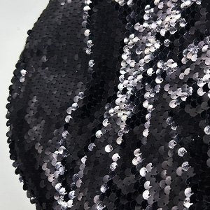 Close-up of black sequins on a fabric surface, showing texture and shine.