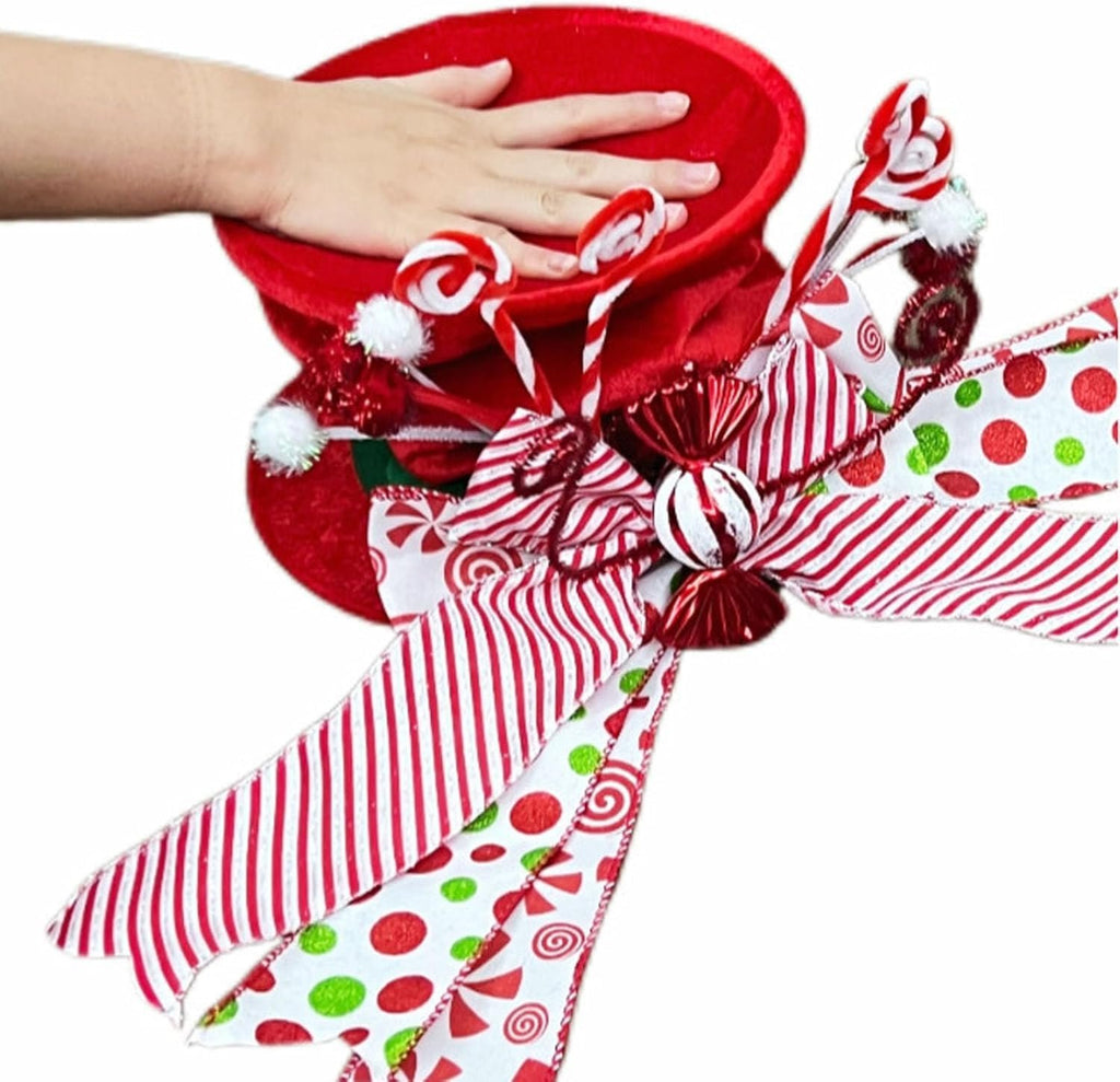 Red velvet Christmas tree topper hat with candy cane accents and festive ribbons, held by a hand.