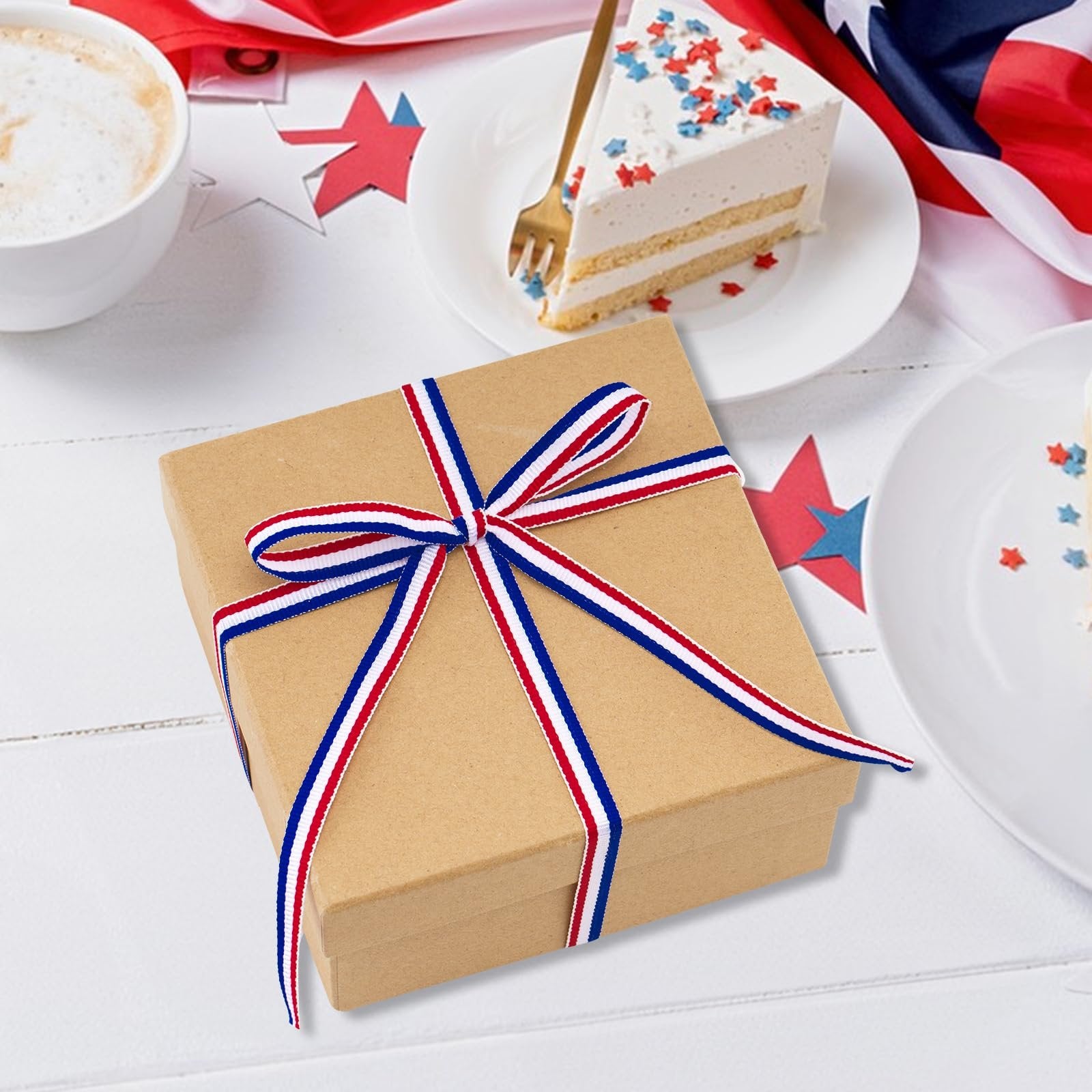 Brown gift box tied with red, white, and blue striped ribbon on a white wooden table with patriotic decorations and cake.