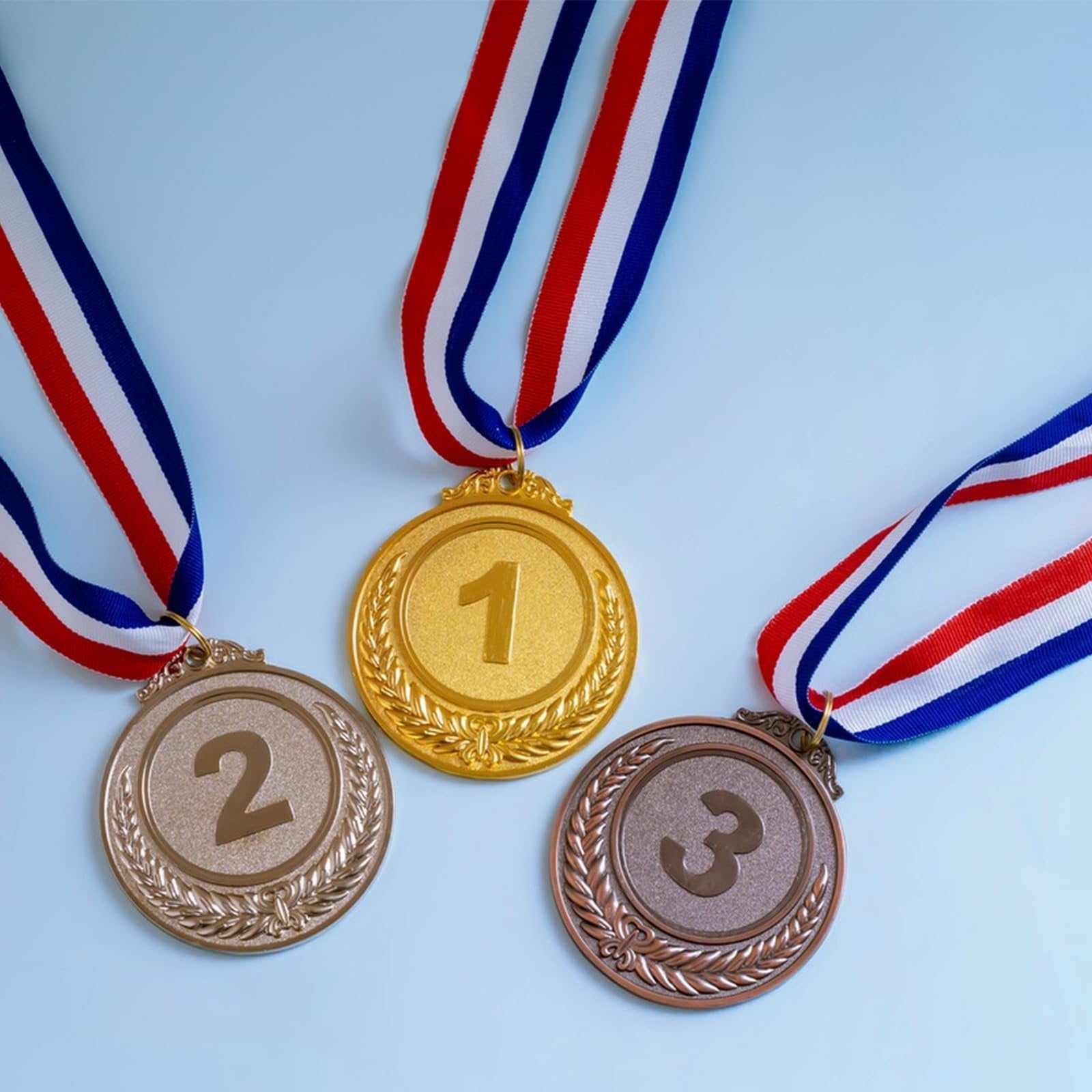 Gold, silver, and bronze medals with red, white, and blue ribbons arranged on a light blue background.
