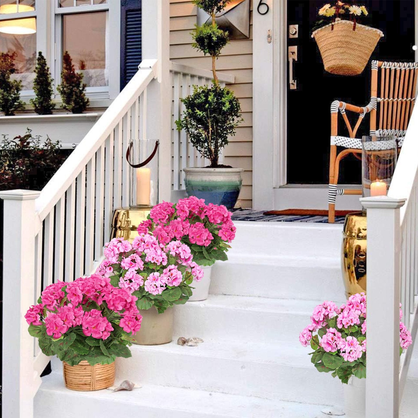 Artificial pink geranium flowers in pots on white porch steps with a chair and straw bag hanging on the door