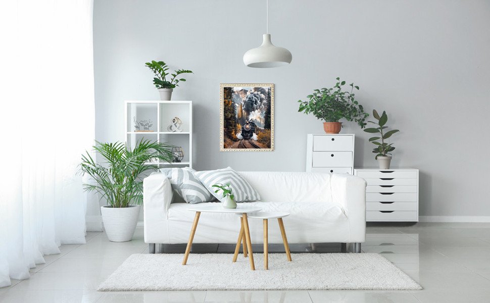 Diamond painting of a steam train on tracks in a forest setting, framed and hanging on a wall above a white sofa.