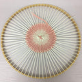 Round wooden knitting loom with white and pink yarn woven in a circular pattern, top-down view.