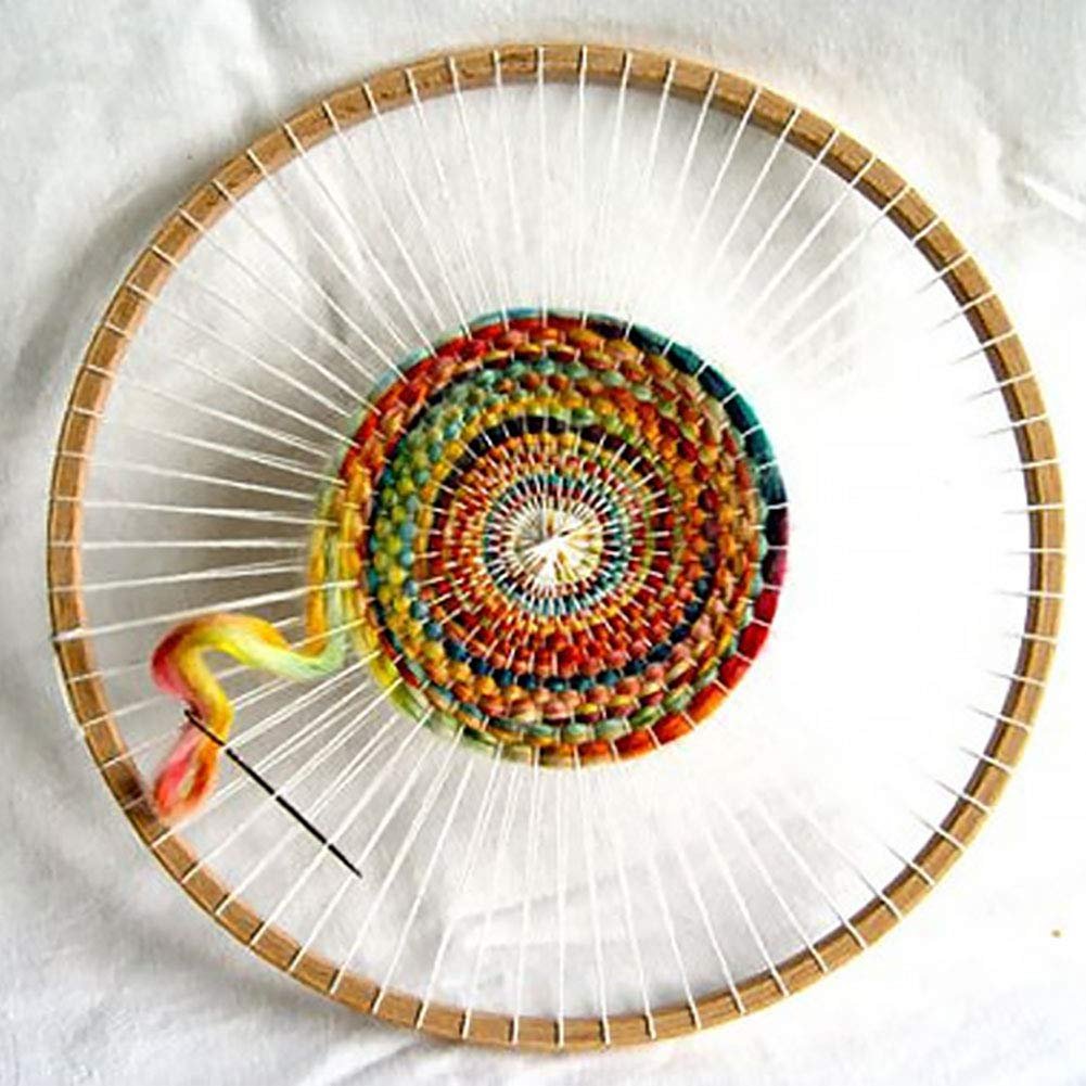 Round wooden knitting loom with colorful yarn woven in a spiral pattern, showing a needle and loose yarn.