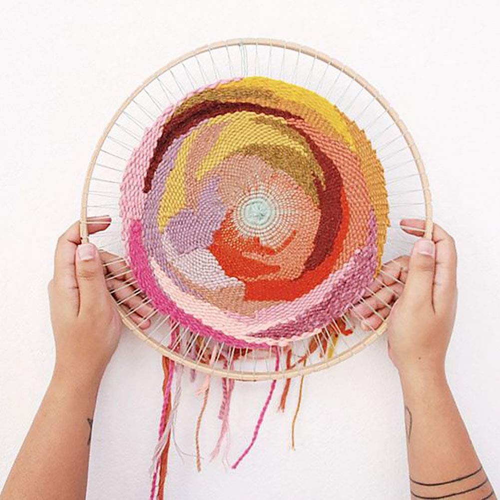 Hands holding a round wooden knitting loom with colorful woven yarn art in progress