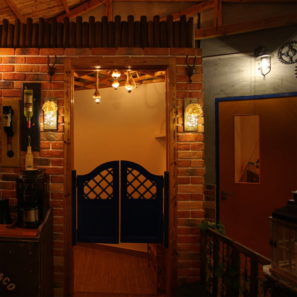 Rustic farmhouse entryway with brick walls, saloon doors, and decorative mason jar lights.