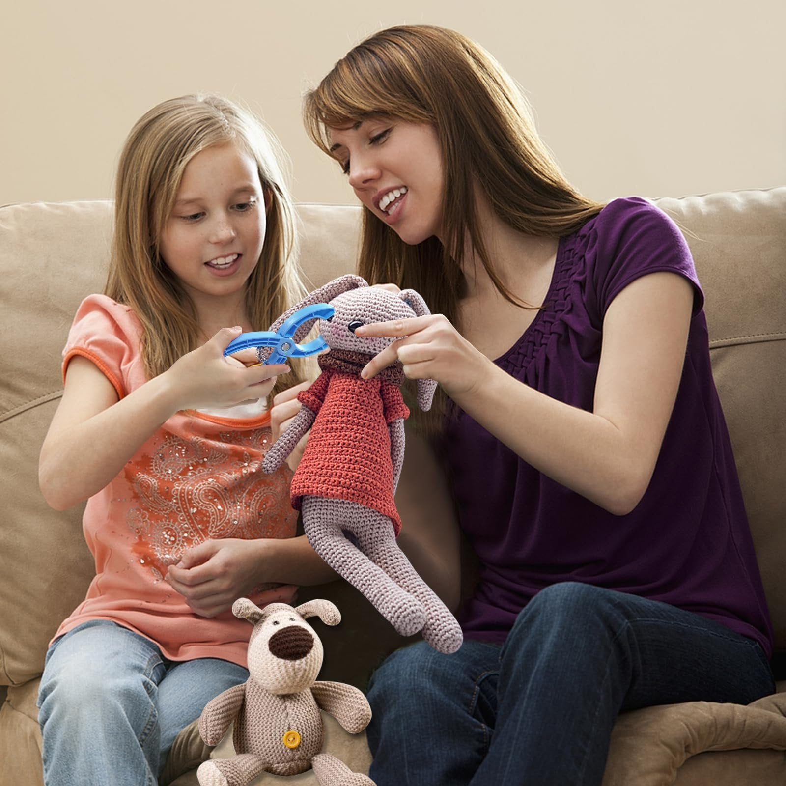 Woman and child using blue safety eye tool to attach eyes to crochet bunny toy on couch