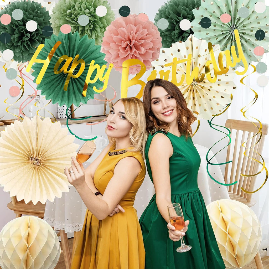 Two women in festive dresses holding champagne glasses at a birthday party with sage green and pink gold decorations.