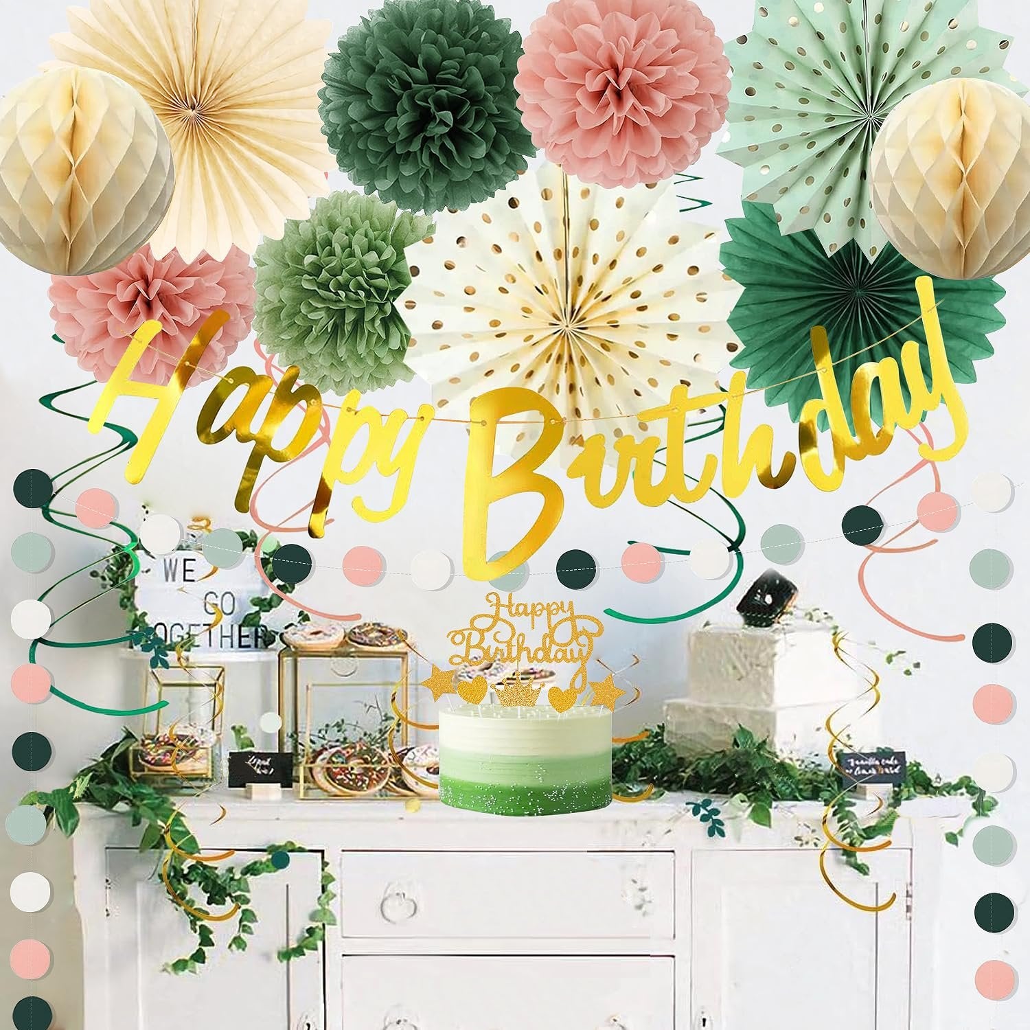 Birthday party decorations including paper fans, pom poms, honeycombs, and a 'Happy Birthday' banner displayed above a cake and desserts.