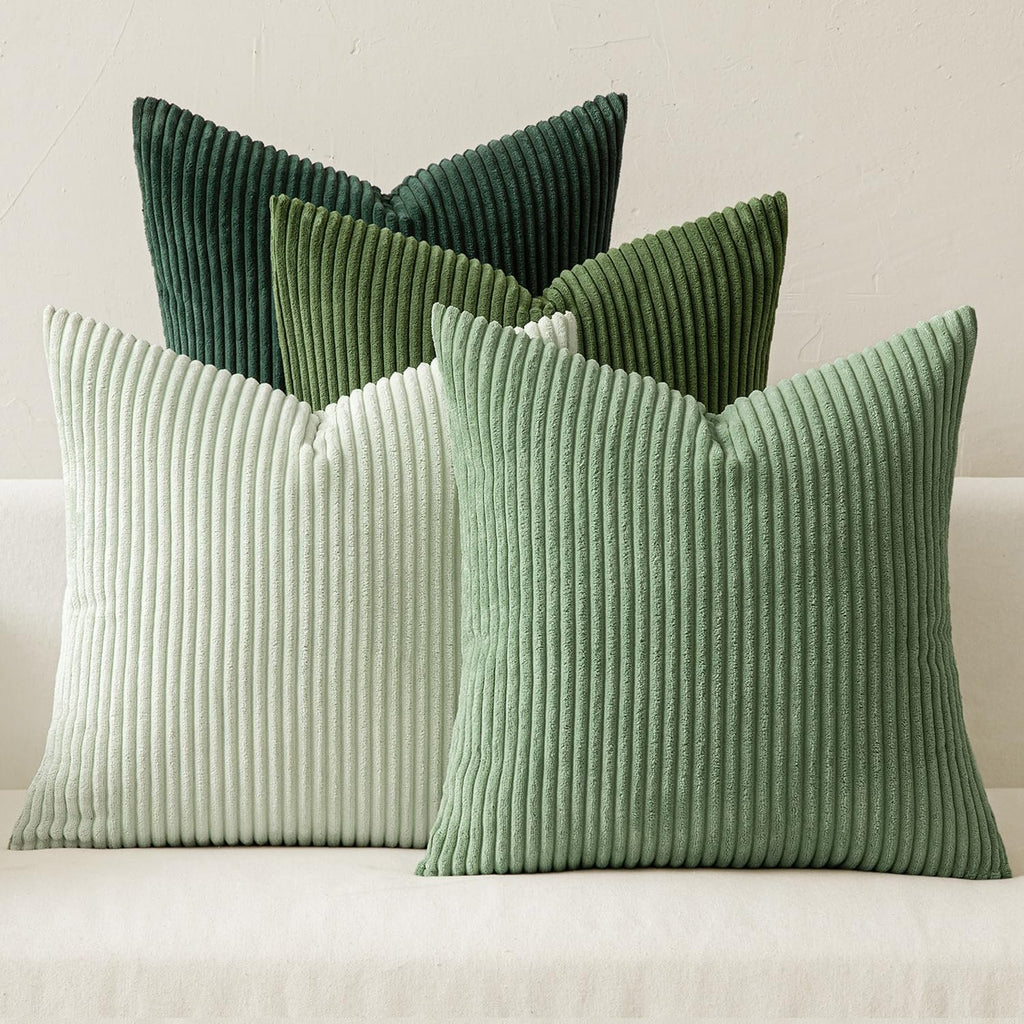 Four corduroy throw pillow covers in varying shades of green arranged on a white couch.