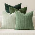 Four corduroy throw pillow covers in varying shades of green arranged on a white couch.